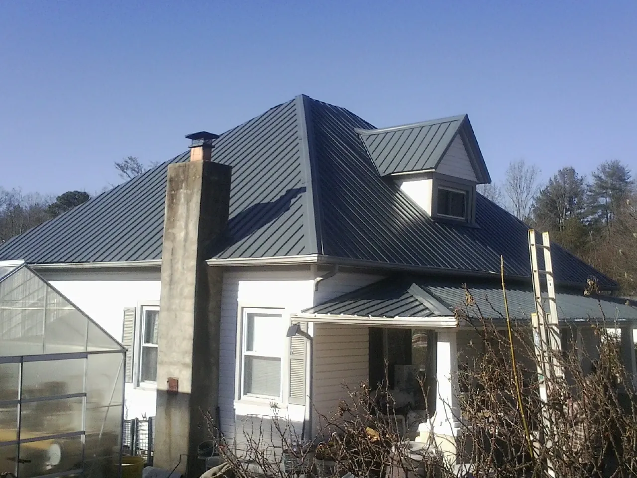 Dark blue standing seam metal roof on a white farmhouse with dormer — Slate & Tile Roof Repair by Roofing Brothers in Gold Bar