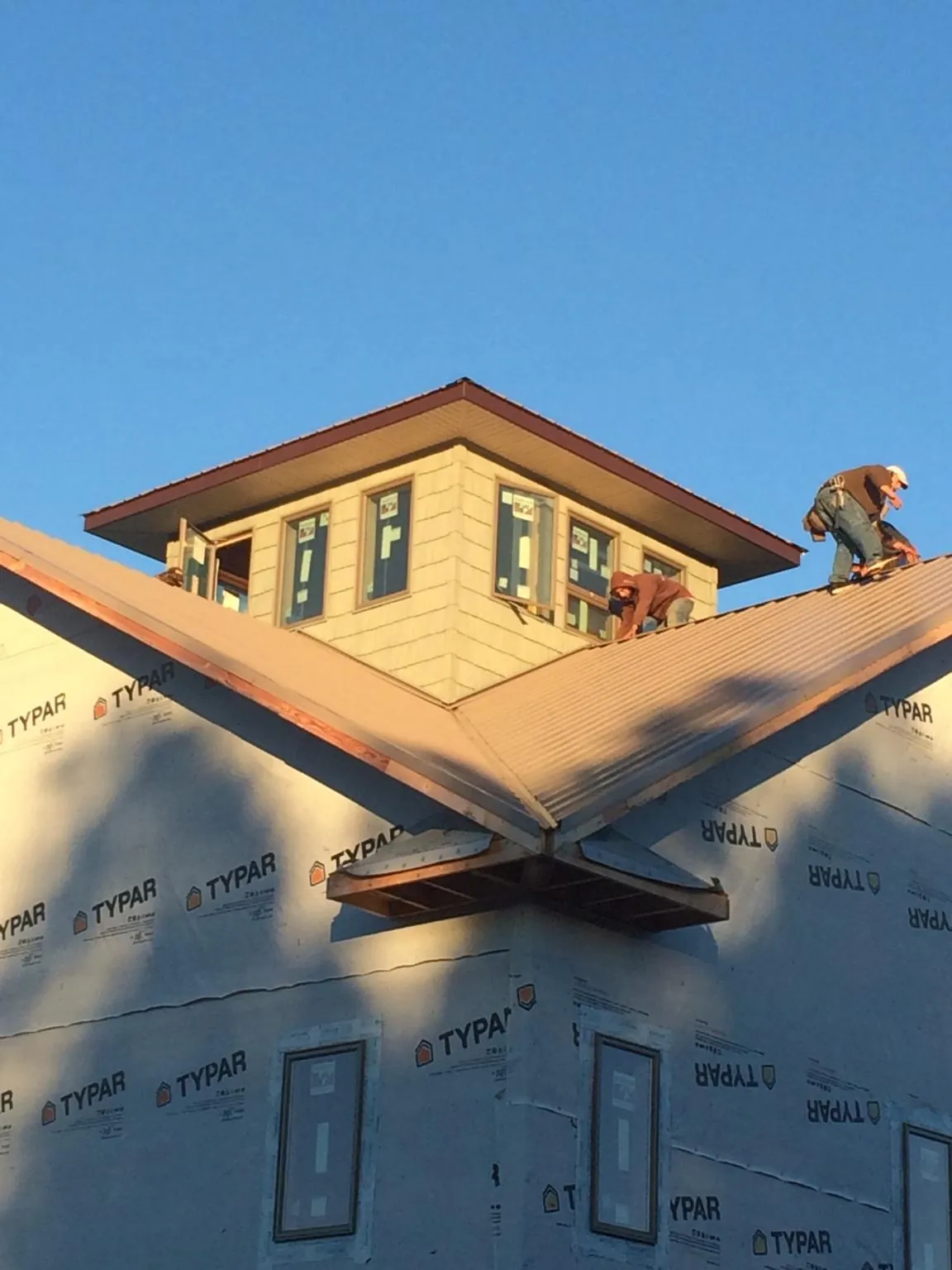 Roofers working around a rooftop cupola on a new metal roof at sunset — Roof Waterproofing in Gold Bar by Roofing Brothers